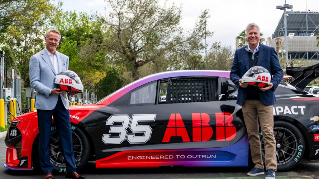 Photo of NASCAR President Steve Phelps and ABB CEO Morton Wierod standing with the ABB NASCAR EV prototype.